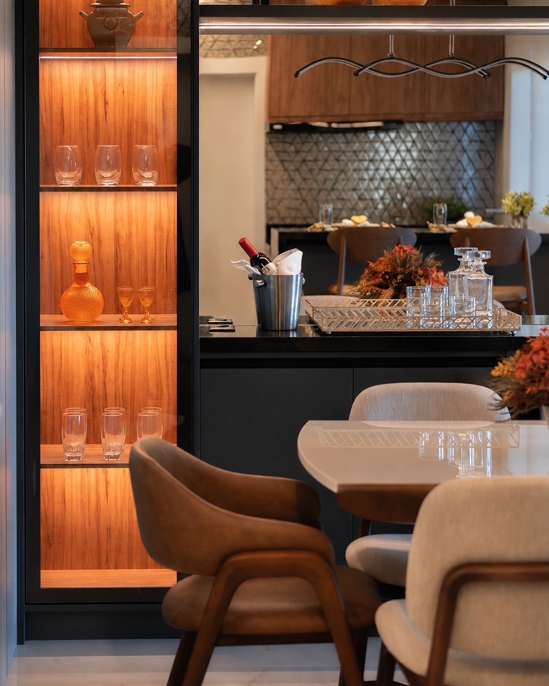 Área gourmet com marcenaria iluminada, adega e mesa de jantar