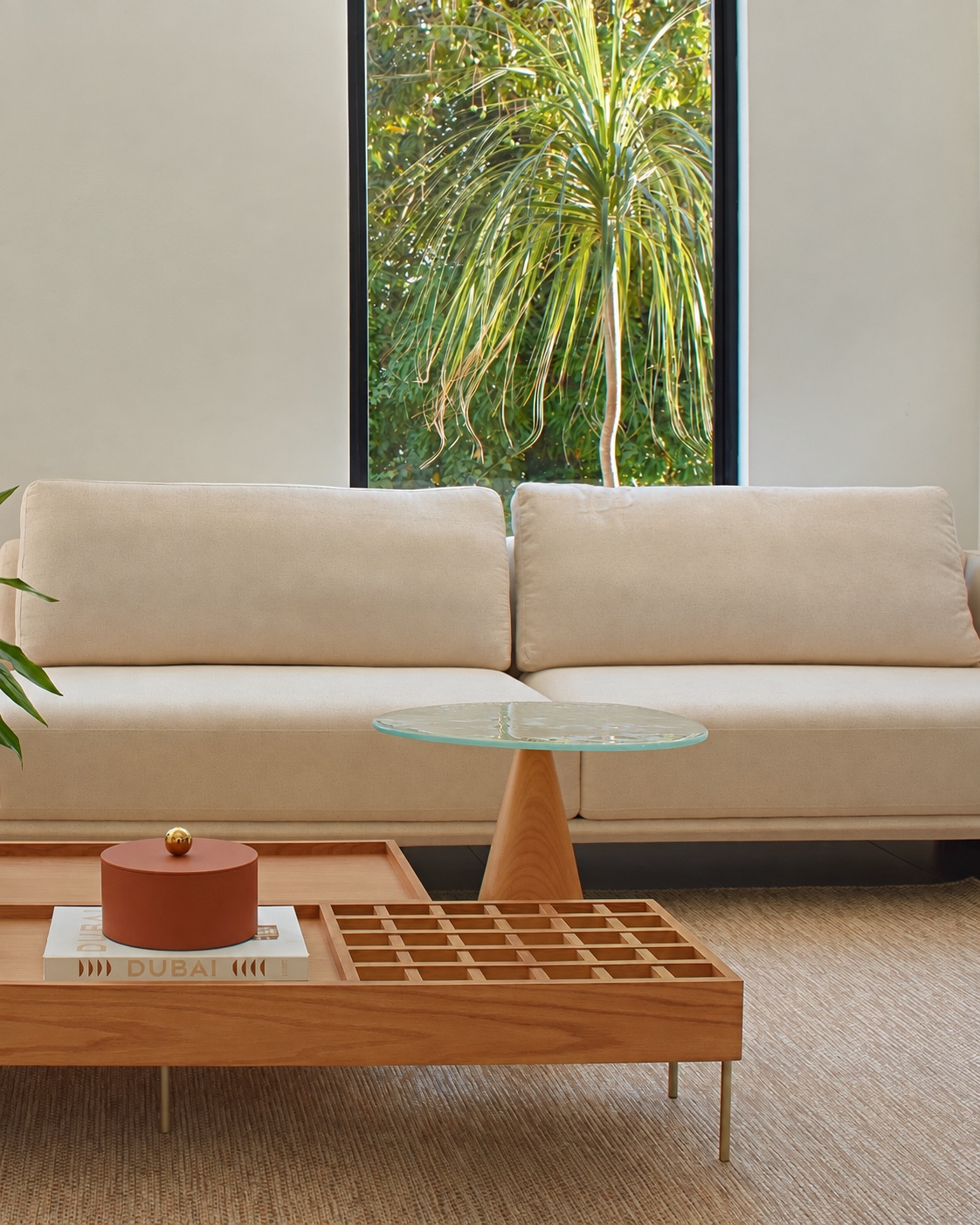Sala de estar com sofá claro, mesa de centro e vista para o jardim